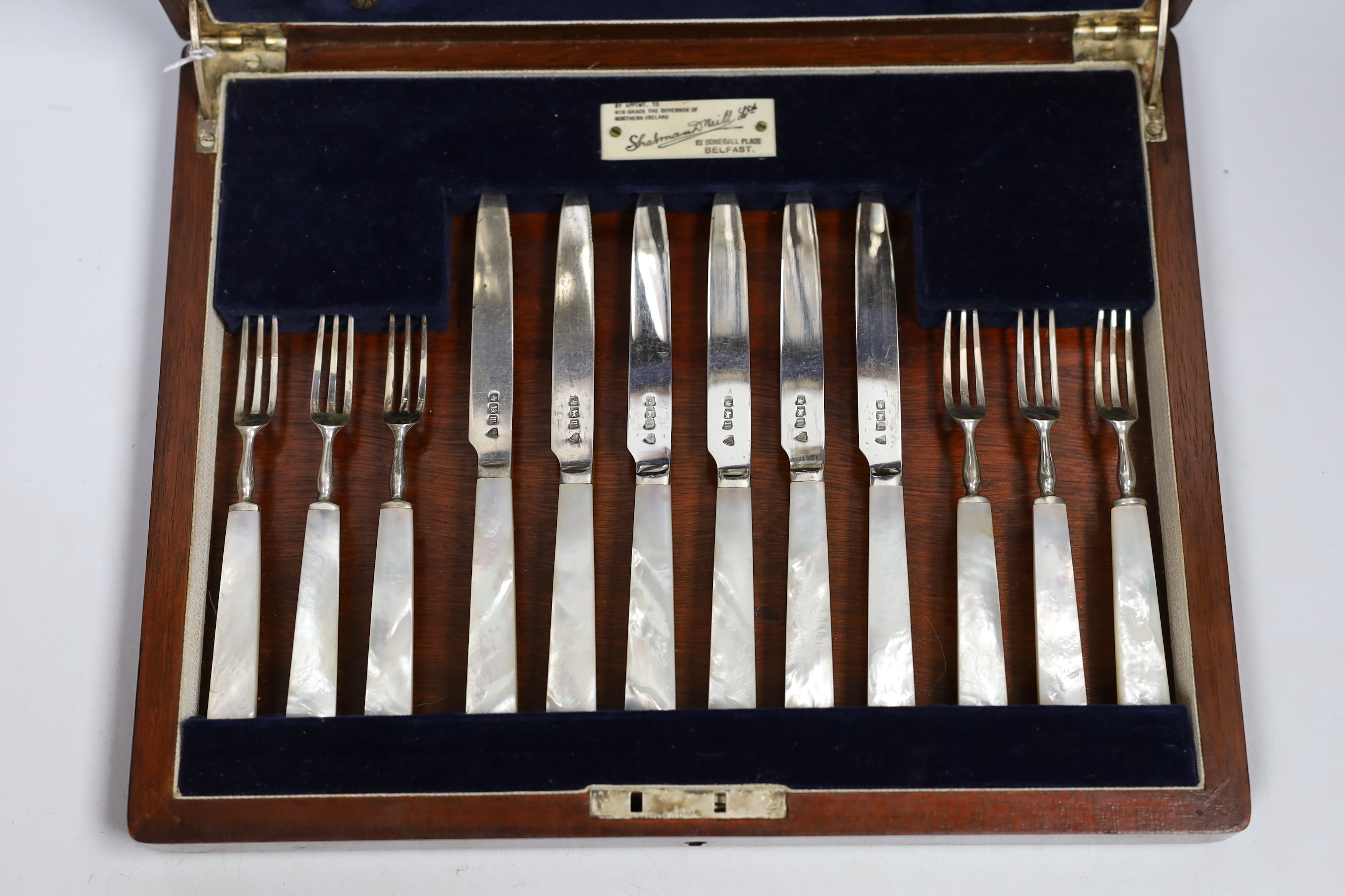 A cased set of twelve pairs of George V silver mother of pearl handled dessert knives and forks, Sheffield 1914, in Belfast Retailer's box